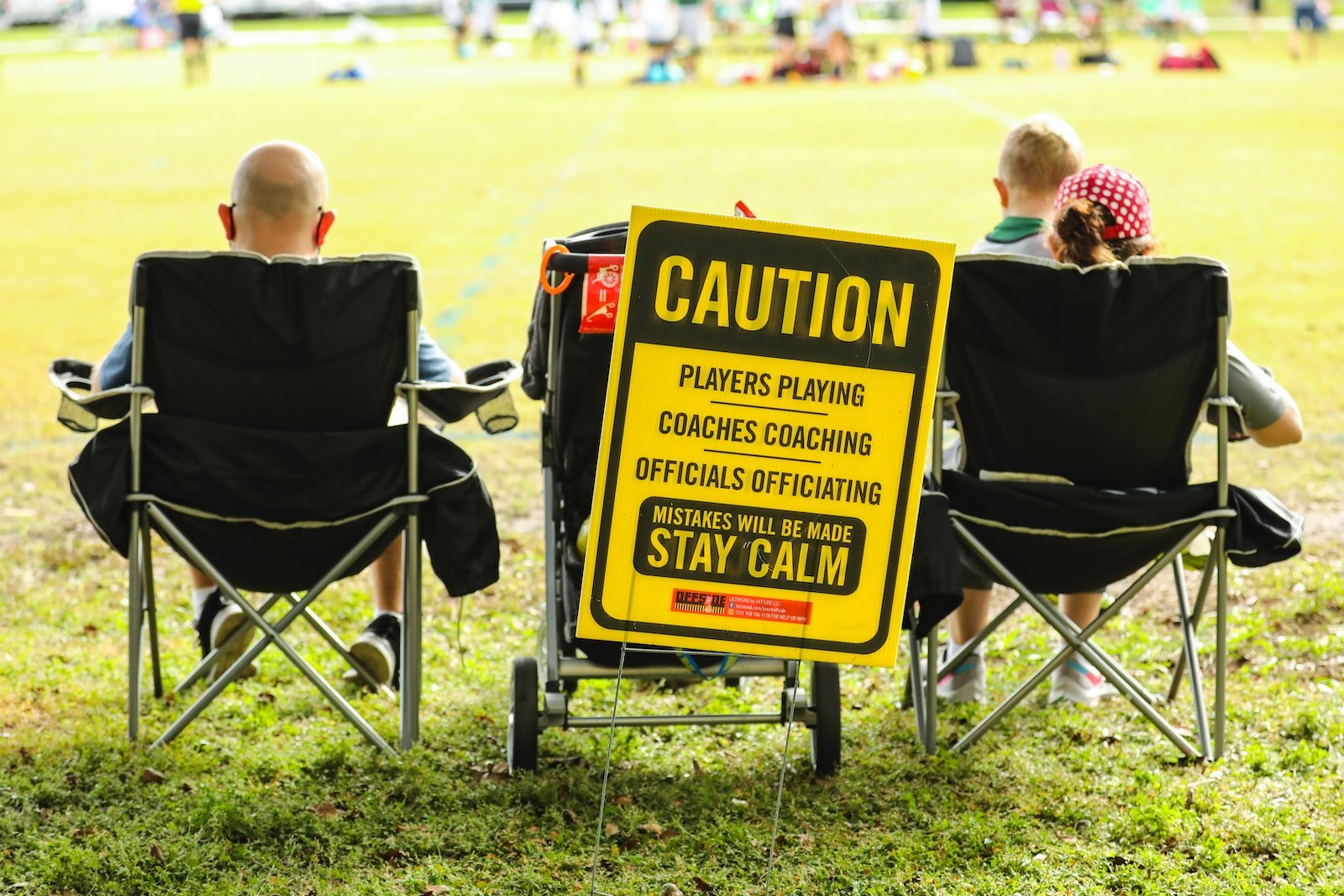 boy in black hoodie sitting on black and yellow folding chair